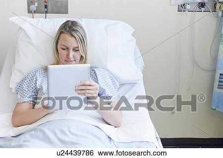 Patient lying on hospital bed using digital tablet View Large Photo Image Stock Photograph - Patient lying on hospital bed using digital tablet. Fotosearch