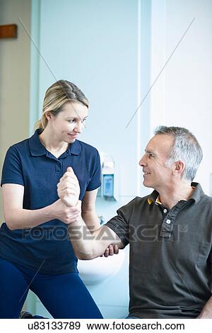 Physiotherapist helping man to do arm exercise View Large Photo Image Stock Photo - Physiotherapist helping man to do arm exercise. Fotosearch