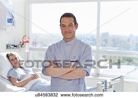 Stock Image - Portrait of nurse standing in front of patient. Fotosearch
