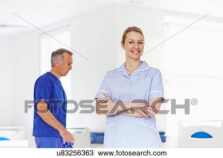 Stock Image - Portrait of nurse with doctor in background. Fotosearch