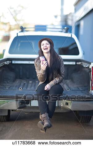Portrait of young female sitting on back of truck View Large Photo Image Stock Photo - Portrait of young female sitting on back of truck. Fotosearch