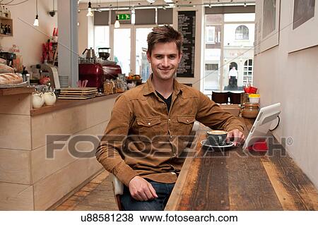 Portrait of young man with coffee and digital tablet in cafe View Large Photo Image Stock Photo - Portrait of young man with coffee and digital tablet in cafe. Fotosearch