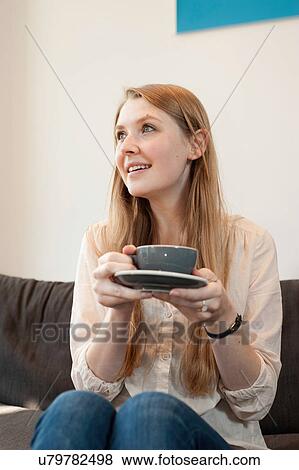 Stock Photo - Portrait of young woman holding coffee cup in cafe. Fotosearch