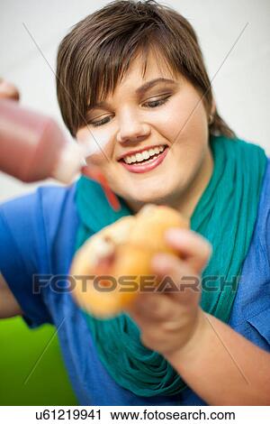 Portrait of young woman holding hotdog View Large Photo Image Stock Image - Portrait of young woman holding hotdog. Fotosearch