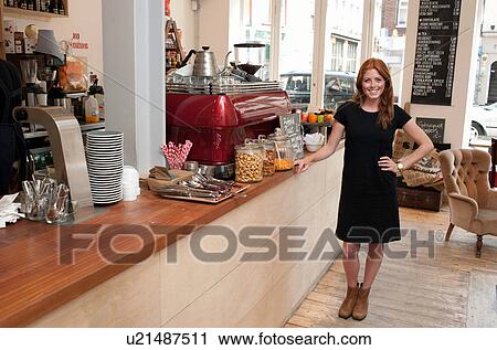 Portrait of young woman standing at cafe counter View Large Photo Image Stock Image - Portrait of young woman standing at cafe counter. Fotosearch