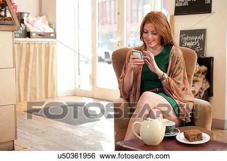 Stock Photograph - Portrait of young woman using smartphone in cafe. Fotosearch