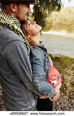 Pregnant woman and partner holding bump View Large Photo Image Stock Photo - Pregnant woman and partner holding bump. Fotosearch