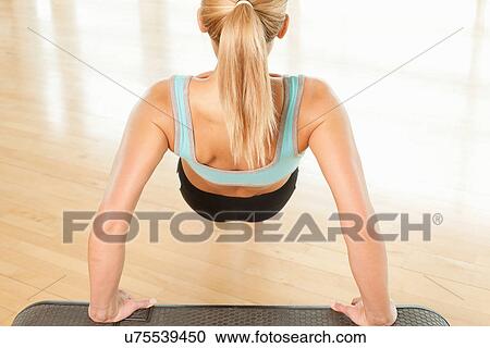 Stock Image - Rear view of woman doing press ups on step. Fotosearch
