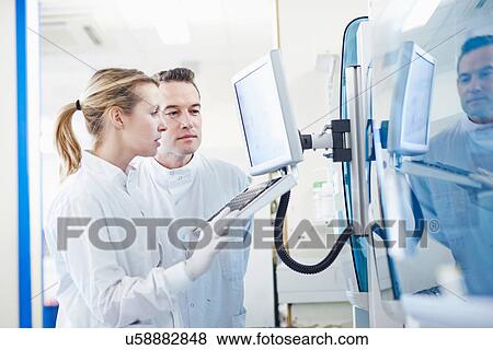 Stock Photo - Researchers looking at computer in lab. Fotosearch