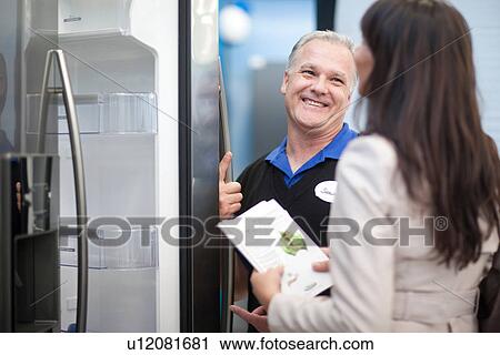 Salesman showing woman fridge in showroom View Large Photo Image Stock Image - Salesman showing woman fridge in showroom. Fotosearch