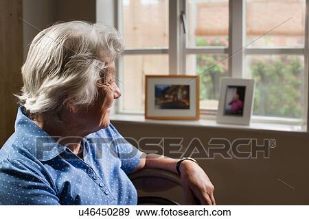 Senior adult woman sitting in room looking out of window View Large Photo Image Stock Photo - Senior adult woman sitting in room looking out of window. Fotosearch