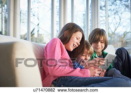 Stock Image - Siblings using digital tablet together. Fotosearch
