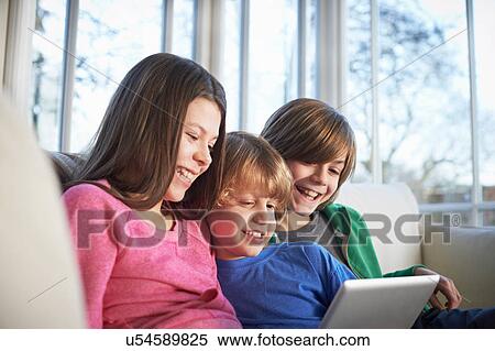 Siblings using digital tablet together View Large Photo Image Stock Photography - Siblings using digital tablet together. Fotosearch