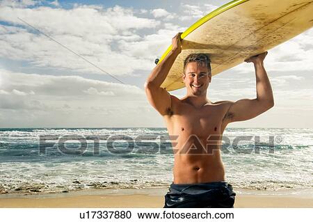 Stock Image - Surfer carrying surf board on head. Fotosearch