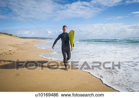 Stock Photograph - Surfer running with surfboard. Fotosearch