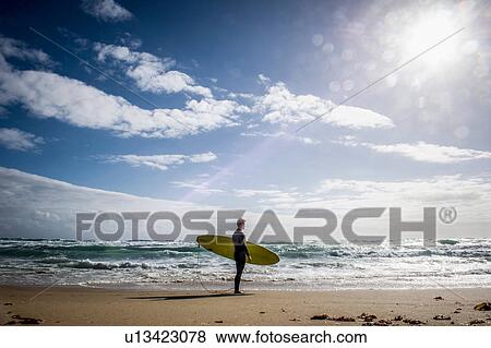 Stock Photo - Surfer standing with surfboard. Fotosearch