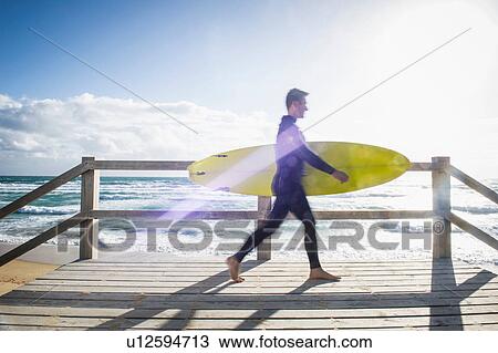 Stock Image - Surfer walking with surfboard. Fotosearch