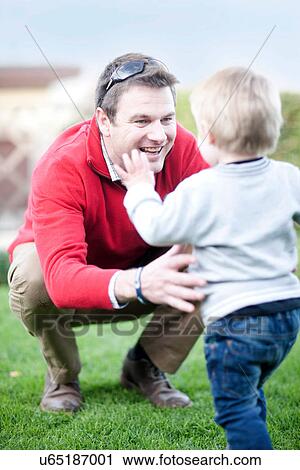 Stock Image - Toddler walking into fathers arms. Fotosearch