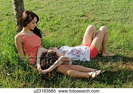 Two young women lounging on grass View Large Photo Image Stock Photography - Two young women lounging on grass. Fotosearch