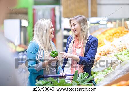 Two young women shopping in indoor market View Large Photo Image Stock Photo - Two young women shopping in indoor market. Fotosearch