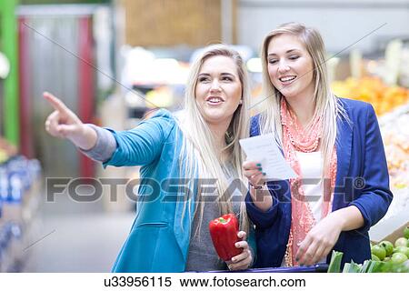 Two young women with shopping list in indoor market View Large Photo Image Stock Photography - Two young women with shopping list in indoor market. Fotosearch