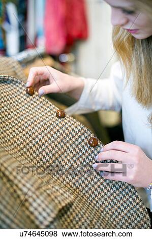 Stock Photo - Woman checking buttons on vintage jacket. Fotosearch