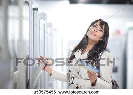 Stock Photography - Woman daydreaming whilst shopping in showroom. Fotosearch