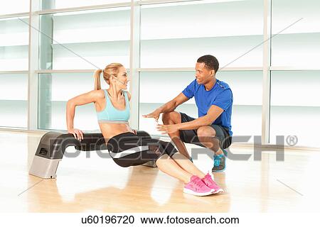 Woman doing exercise on step with man instructing View Large Photo Image Stock Image - Woman doing exercise on step with man instructing. Fotosearch