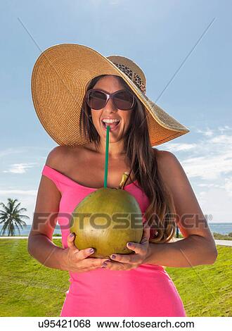 Stock Photo - Woman drinking coconut juice with straw. Fotosearch