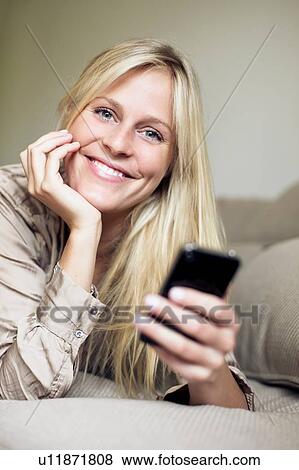Woman holding mobile phone in bed View Large Photo Image Stock Photo - Woman holding mobile phone in bed. Fotosearch