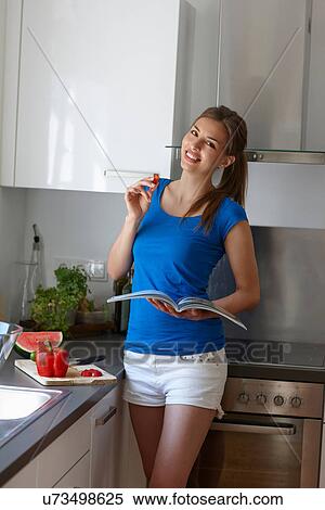 Stock Photography - Woman holding up book and slice of red pepper. Fotosearch