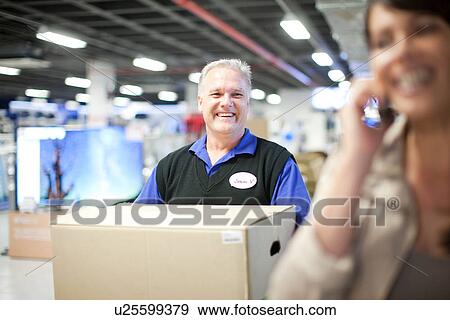Woman leaving showroom with salesman carrying purchase View Large Photo Image Stock Photo - Woman leaving showroom with salesman carrying purchase. Fotosearch