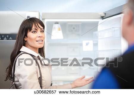 Woman looking at fridge in showroom View Large Photo Image Stock Photo - Woman looking at fridge in showroom. Fotosearch