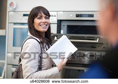 Stock Photo - Woman looking at oven in showroom. Fotosearch