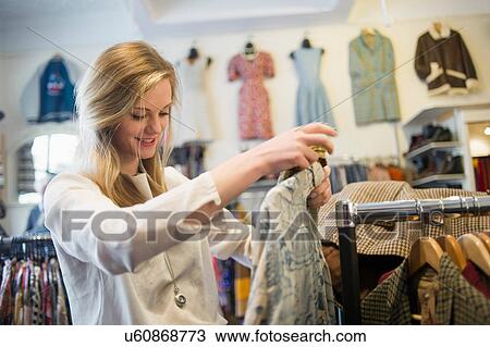 Woman looking at top garment View Large Photo Image Stock Image - Woman looking at top garment. Fotosearch