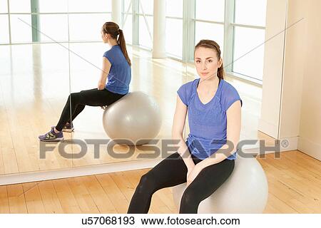 Stock Image - Woman on exercise ball in gymnasium. Fotosearch