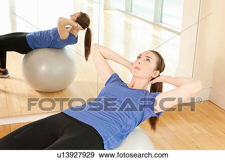 Stock Photo - Woman on exercise ball in gymnasium. Fotosearch