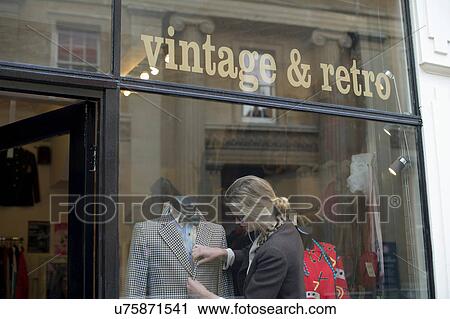 Stock Image - Woman putting jacket on shop dummy. Fotosearch