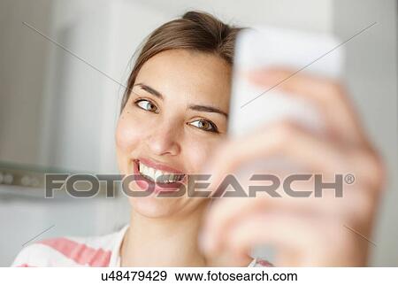 Woman smiling and looking at mobile phone View Large Photo Image Stock Photo - Woman smiling and looking at mobile phone. Fotosearch