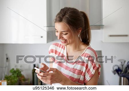 Stock Photograph - Woman smiling and using mobile phone. Fotosearch