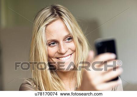 Picture - Woman smiling at mobile phone. Fotosearch