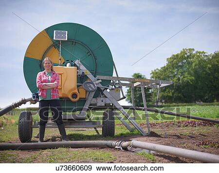 Woman standing by irrigation system View Large Photo Image Stock Photo - Woman standing by irrigation system. Fotosearch