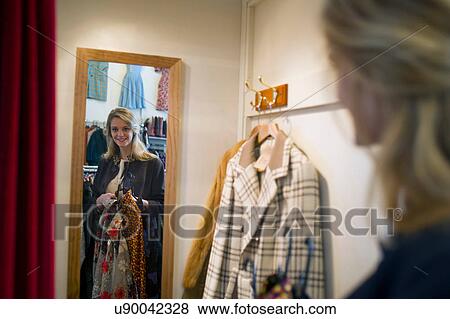 Stock Photo - Woman taking clothes into fitting room. Fotosearch