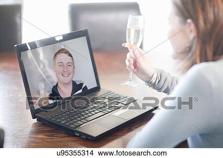 Woman toasting husband using video call View Large Photo Image Picture - Woman toasting husband using video call. Fotosearch