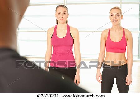Stock Image - Women standing together in exercise class. Fotosearch