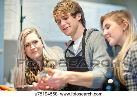 Young adults preparing food in kitchen View Large Photo Image Stock Photo - Young adults preparing food in kitchen. Fotosearch