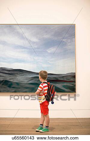 Stock Image - Young boy looking at picture in gallery. Fotosearch