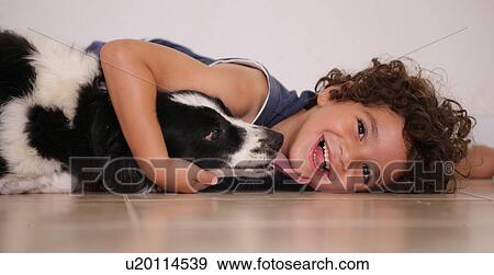 Young boy lying on floor hugging his pet dog View Large Photo Image Stock Photo - Young boy lying on floor hugging his pet dog. Fotosearch