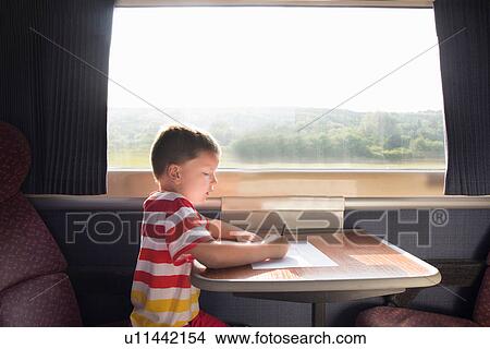 Picture - Young boy with pencil and paper on train. Fotosearch