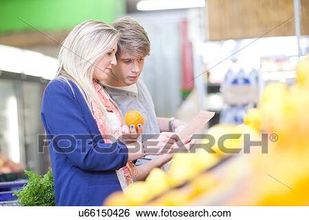 Stock Photograph - Young couple buying oranges in indoor market. Fotosearch